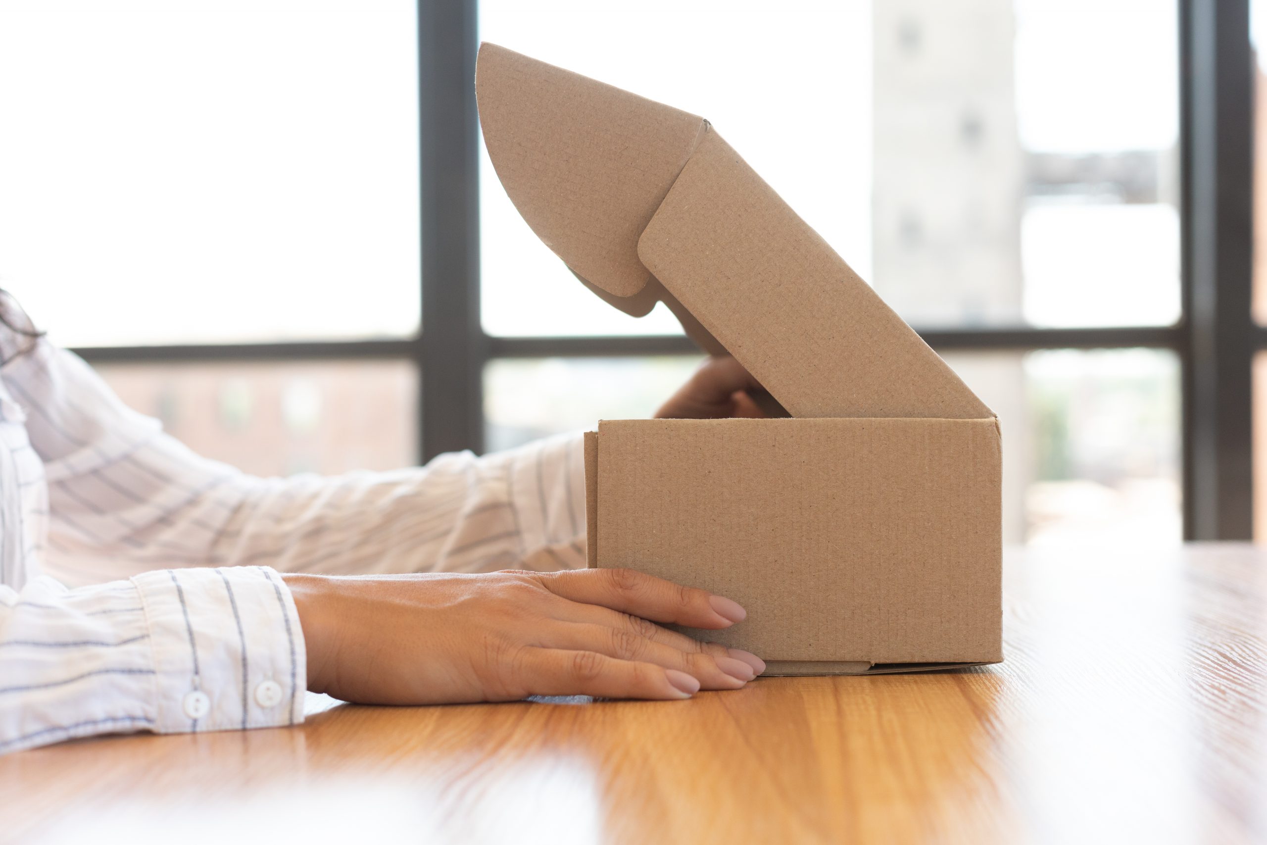 Handen openen een kartonnen doos op een houten tafel